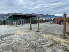 A fenced in area with a building in the background

Description automatically generated