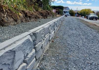 A stone wall along a road

Description automatically generated