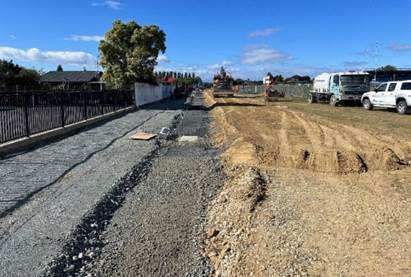 A road with a few trucks and a fence

Description automatically generated with medium confidence