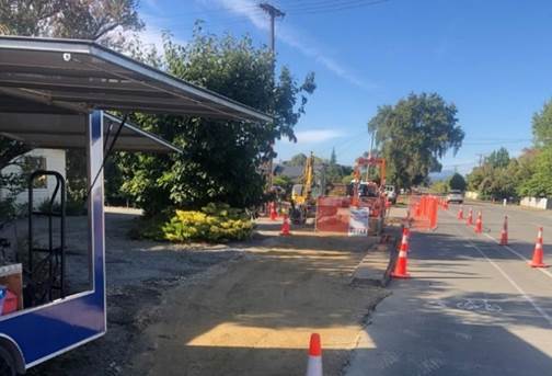 A road with orange cones and a blue sign

Description automatically generated