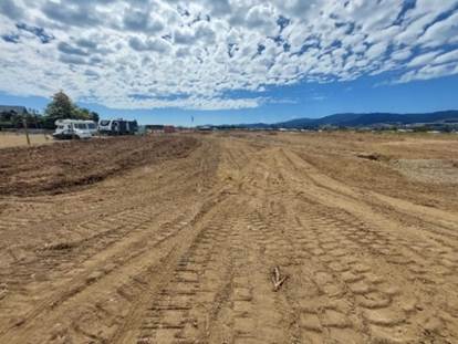 A dirt field with a few vehicles parked in the background

Description automatically generated
