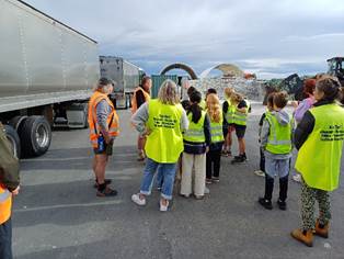 A group of people in yellow vests standing in front of a truck

Description automatically generated