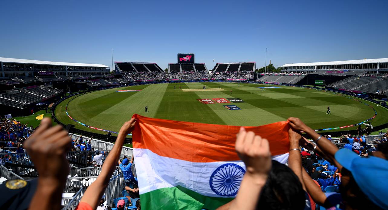 A group of people holding a flag in front of a stadium

Description automatically generated