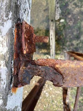 A rusty metal piece with a bolt

Description automatically generated