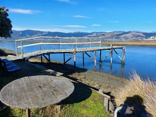 A wooden dock with a table and a round table on a body of water

AI-generated content may be incorrect.